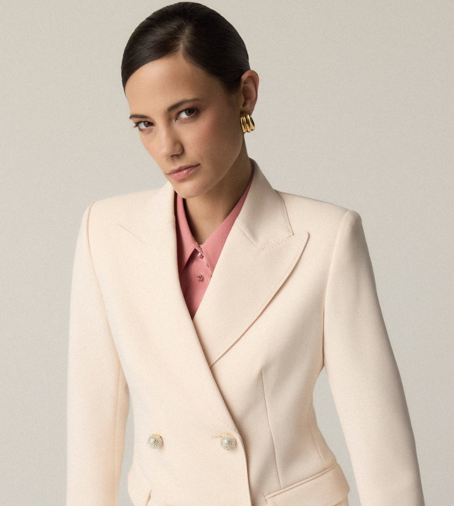 Woman wearing St John Knits hoop earing with ivory double-breasted jacket. 